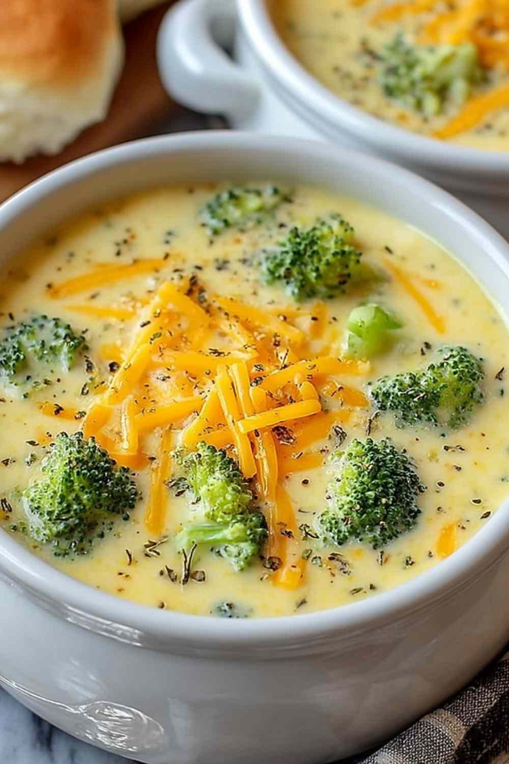 Homemade broccoli cheddar soup served in a rustic bowl topped with melted cheddar and fresh broccoli florets