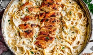 Chicken Alfredo Creamy Chicken Alfredo recipe served in a large skillet with sliced chicken, fettuccine, and fresh parsley