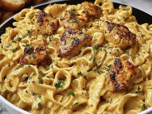 Creamy Cowboy Butter Chicken Pasta in a skillet with golden chicken slices and garlic butter cream sauce over fettuccine