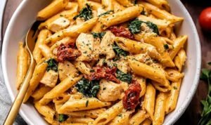 Creamy marry me chicken pasta in a large skillet topped with fresh basil and grated Parmesan cheese