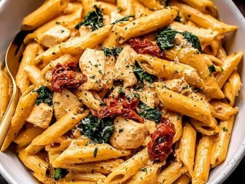 Creamy marry me chicken pasta in a large skillet topped with fresh basil and grated Parmesan cheese