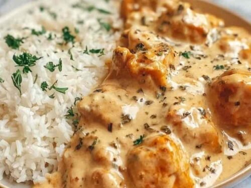 Creamy smothered chicken and rice served in a skillet with mushroom cream sauce and fresh parsley