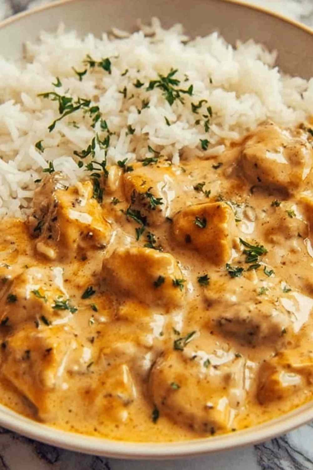 Creamy smothered chicken and rice served in a skillet with mushroom cream sauce and fresh parsley