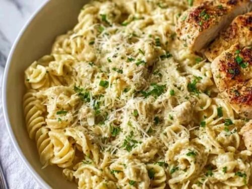 Creamy garlic parmesan chicken pasta served in a skillet topped with fresh parsley and grated Parmesan cheese