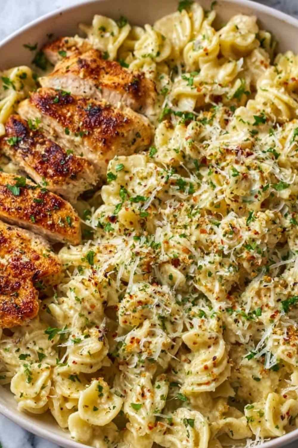 Creamy garlic parmesan chicken pasta served in a skillet topped with fresh parsley and grated Parmesan cheese