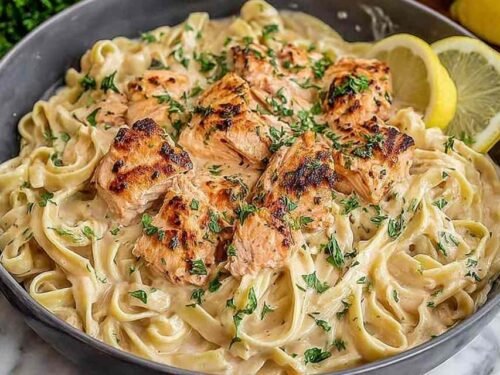 Creamy salmon pasta with fettuccine and parmesan cream sauce in a large skillet topped with fresh dill