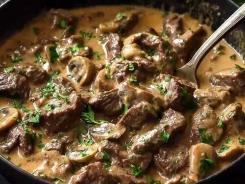 Gordon Ramsay's beef stroganoff served over buttered egg noodles with fresh chives in a cast iron skillet