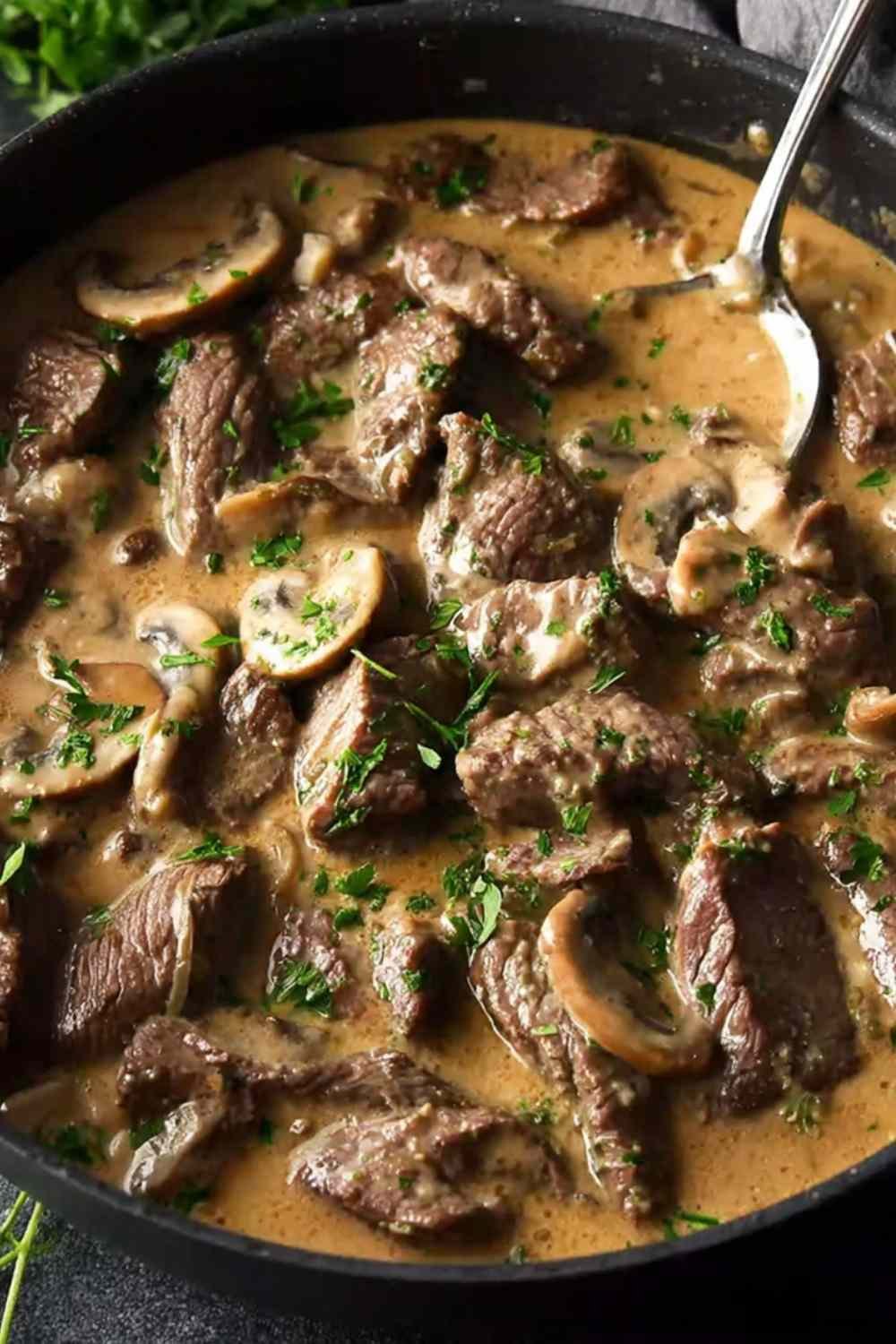 Gordon Ramsay's beef stroganoff served over buttered egg noodles with fresh chives in a cast iron skillet