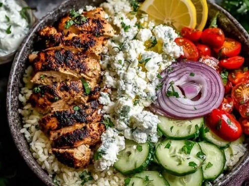 Greek Chicken Bowls in a white bowl with fresh vegetables and feta cheese