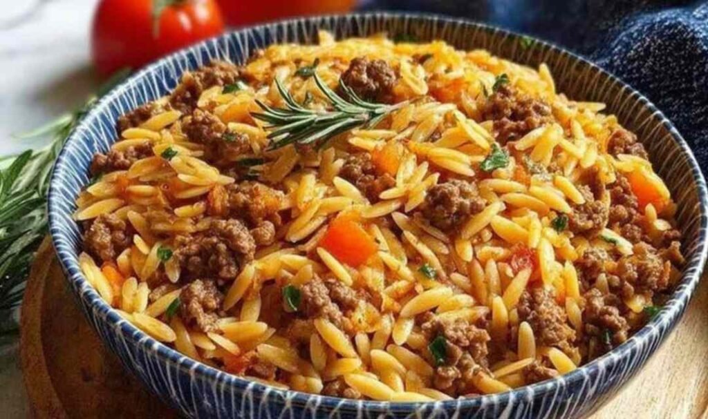 Creamy ground beef orzo recipe served in a large skillet topped with freshly grated Parmesan cheese