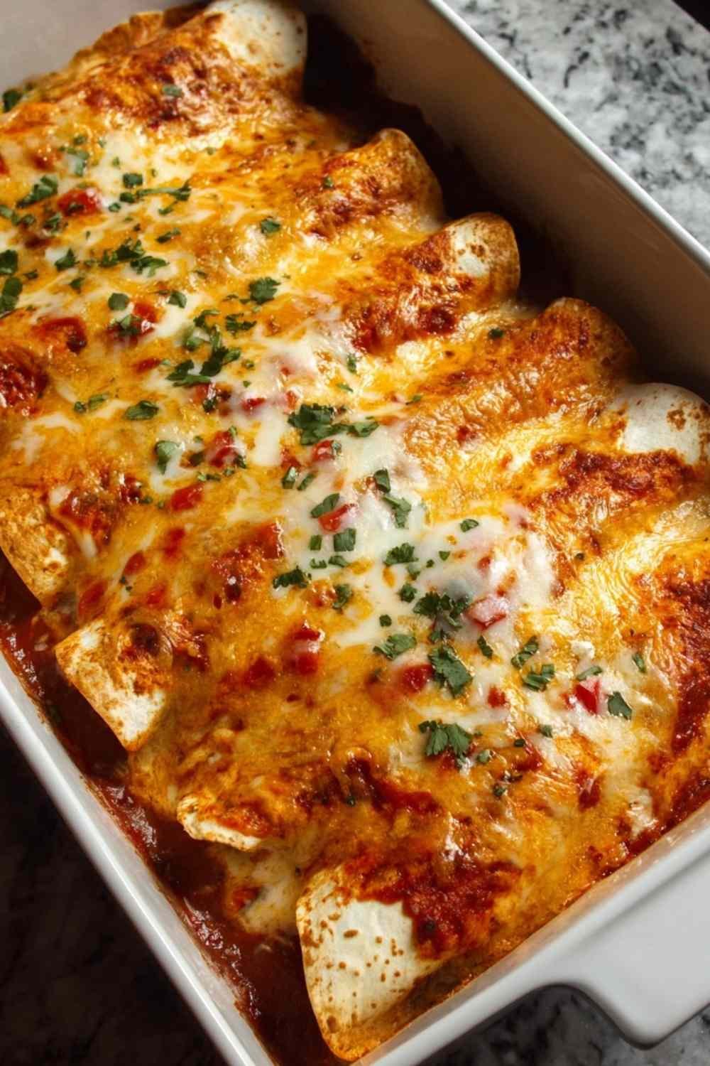 Queso Chicken Enchiladas baking in a glass dish with melted cheese
