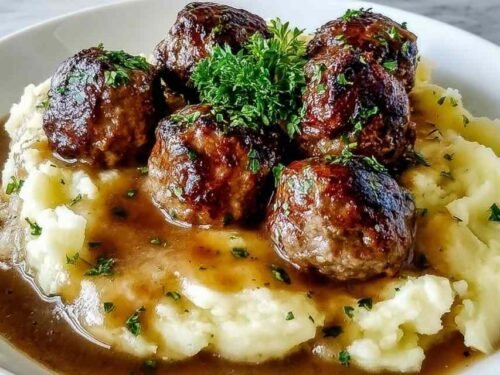 Salisbury Steak Meatballs with gravy served over garlic mashed potatoes on a white plate
