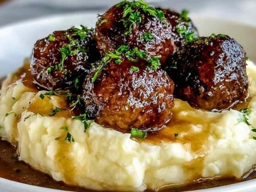 Salisbury Steak Meatballs served with garlic mashed potatoes and gravy on a white plate