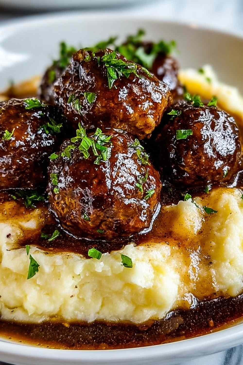 Salisbury Steak Meatballs served with garlic mashed potatoes and gravy on a white plate