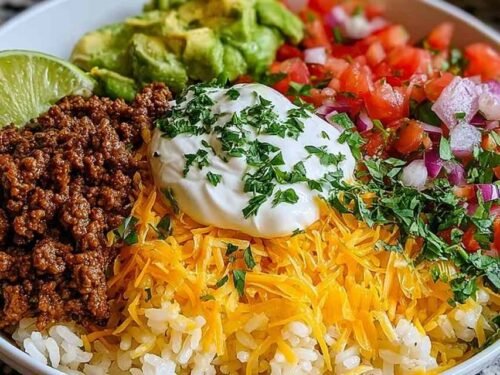 Fresh ingredients for a Taco Rice Bowl including ground meat, rice, and vegetables.