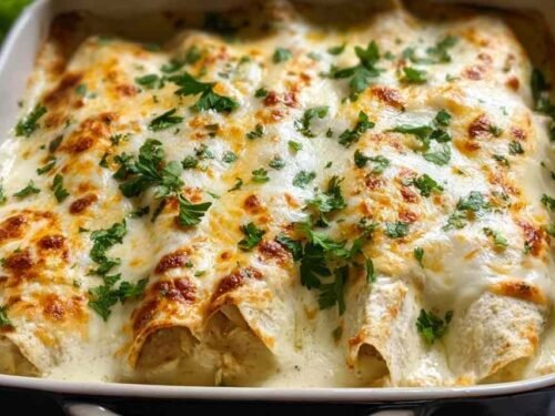Creamy white chicken enchiladas baked in a 9x13 dish with golden melted cheese
