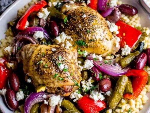 Greek chicken with veggies in a cast iron skillet topped with feta cheese and Kalamata olives