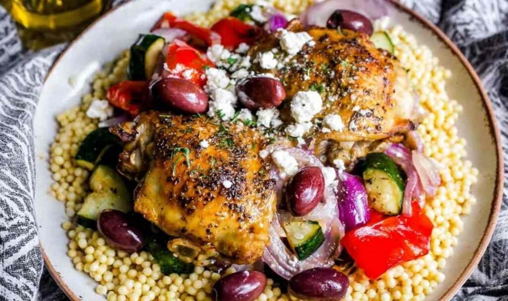 Greek chicken with veggies in a cast iron skillet topped with feta cheese and Kalamata olives
