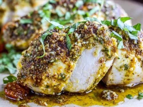 Baked pesto chicken spread with basil mixture on a baking sheet