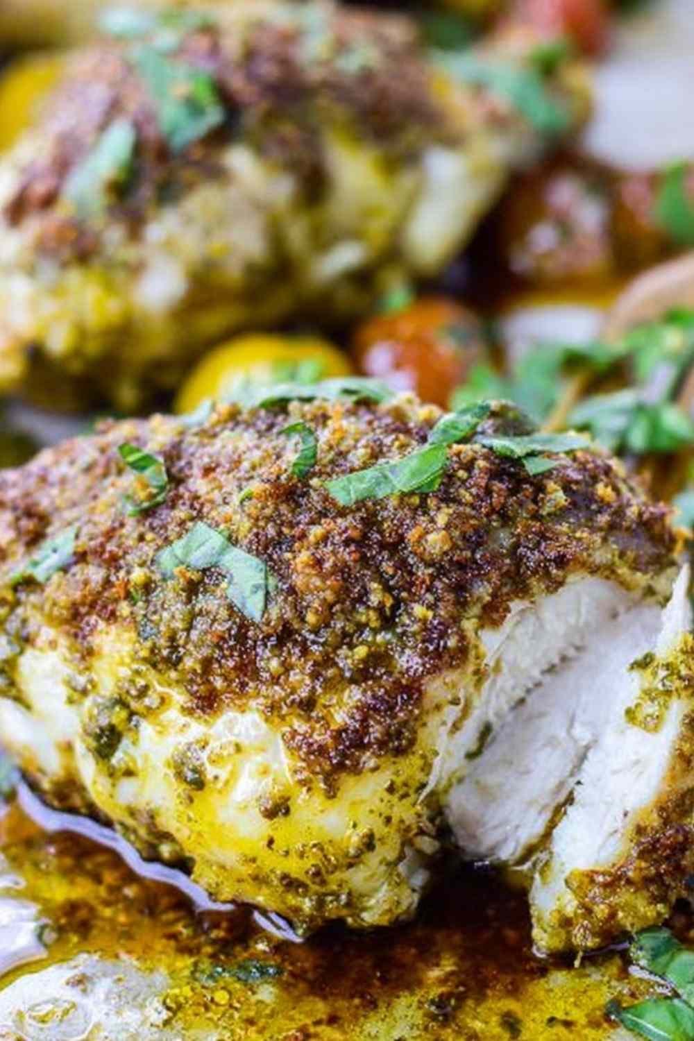 Baked pesto chicken spread with basil mixture on a baking sheet