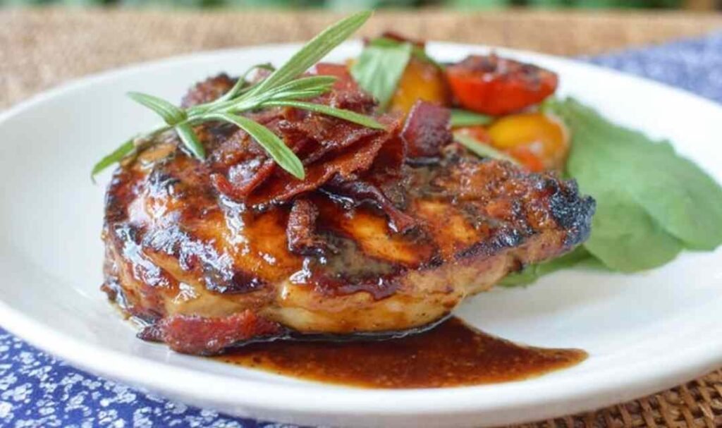 Juicy grilled chicken spicy honey bacon glaze served on a white plate with grilled vegetables