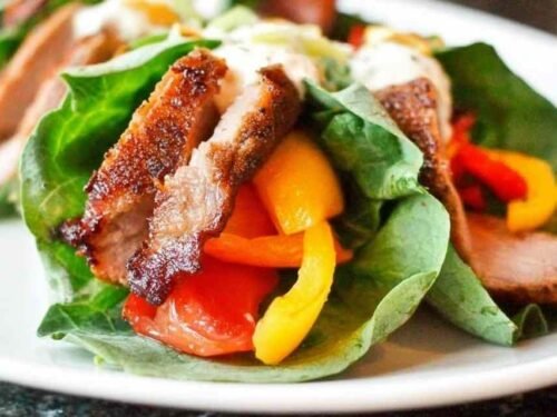 Sliced barbeque pork tenderloin on a white plate seasoned with a smoky homemade dry rub