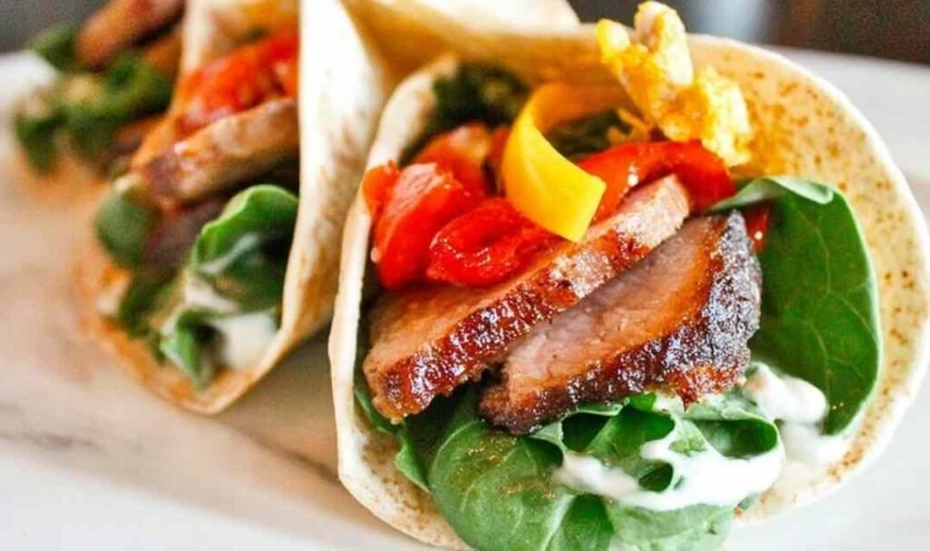 Sliced barbeque pork tenderloin on a white plate seasoned with a smoky homemade dry rub