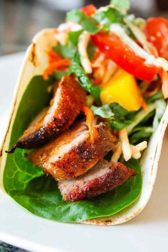 Sliced barbeque pork tenderloin on a white plate seasoned with a smoky homemade dry rub