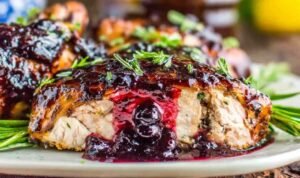 Blackberry balsamic glazed chicken breasts served on a white plate with fresh blackberries and balsamic glaze