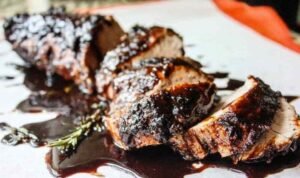 Sliced brown sugar balsamic pork tenderloin crock pot recipe on a white serving platter with sticky caramelized glaze