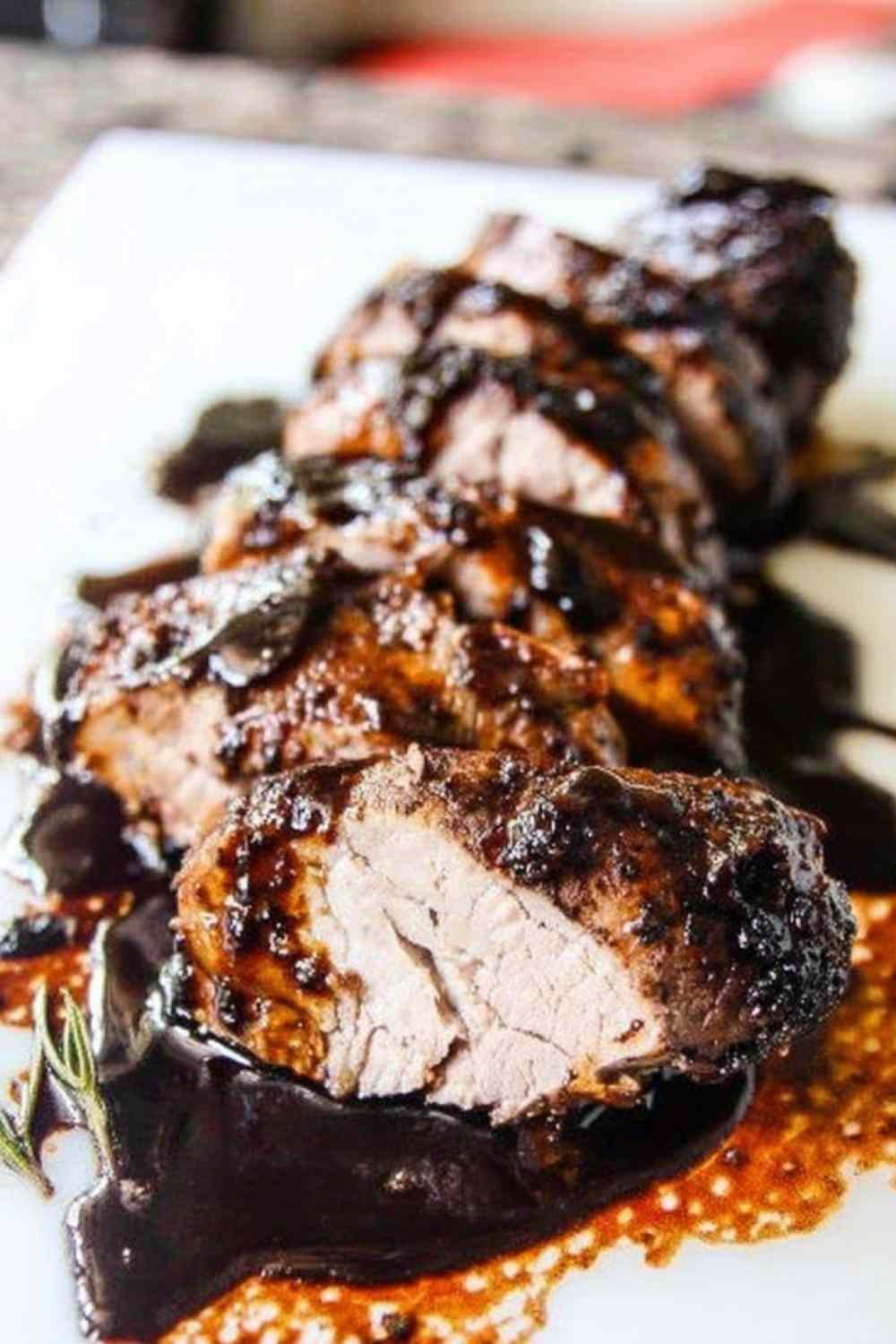 Sliced brown sugar balsamic pork tenderloin crock pot recipe on a white serving platter with sticky caramelized glaze