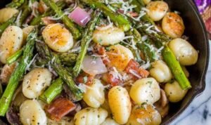 Brown butter gnocchi with asparagus and prosciutto Brown butter gnocchi with asparagus and prosciutto in a cast iron skillet topped with freshly grated Parmesan cheese