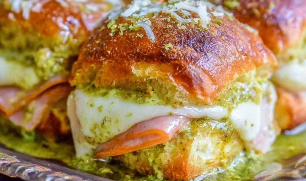 Canadian Bacon and Havarti Cheese Sliders with pesto glaze on a baking sheet, golden and bubbly fresh from the oven