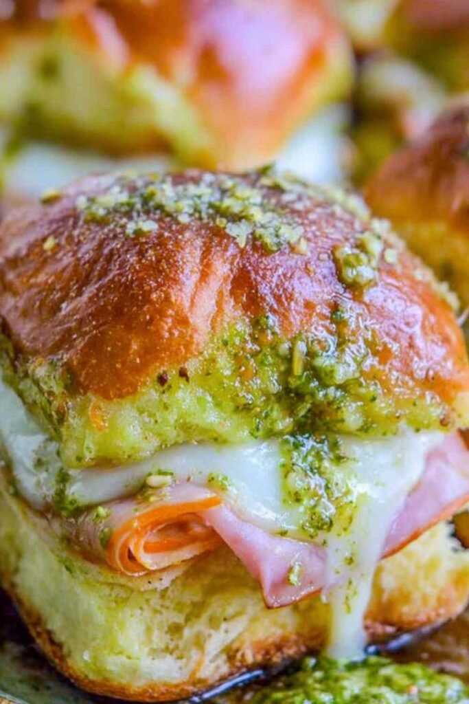 Canadian Bacon and Havarti Cheese Sliders with pesto glaze on a baking sheet, golden and bubbly fresh from the oven