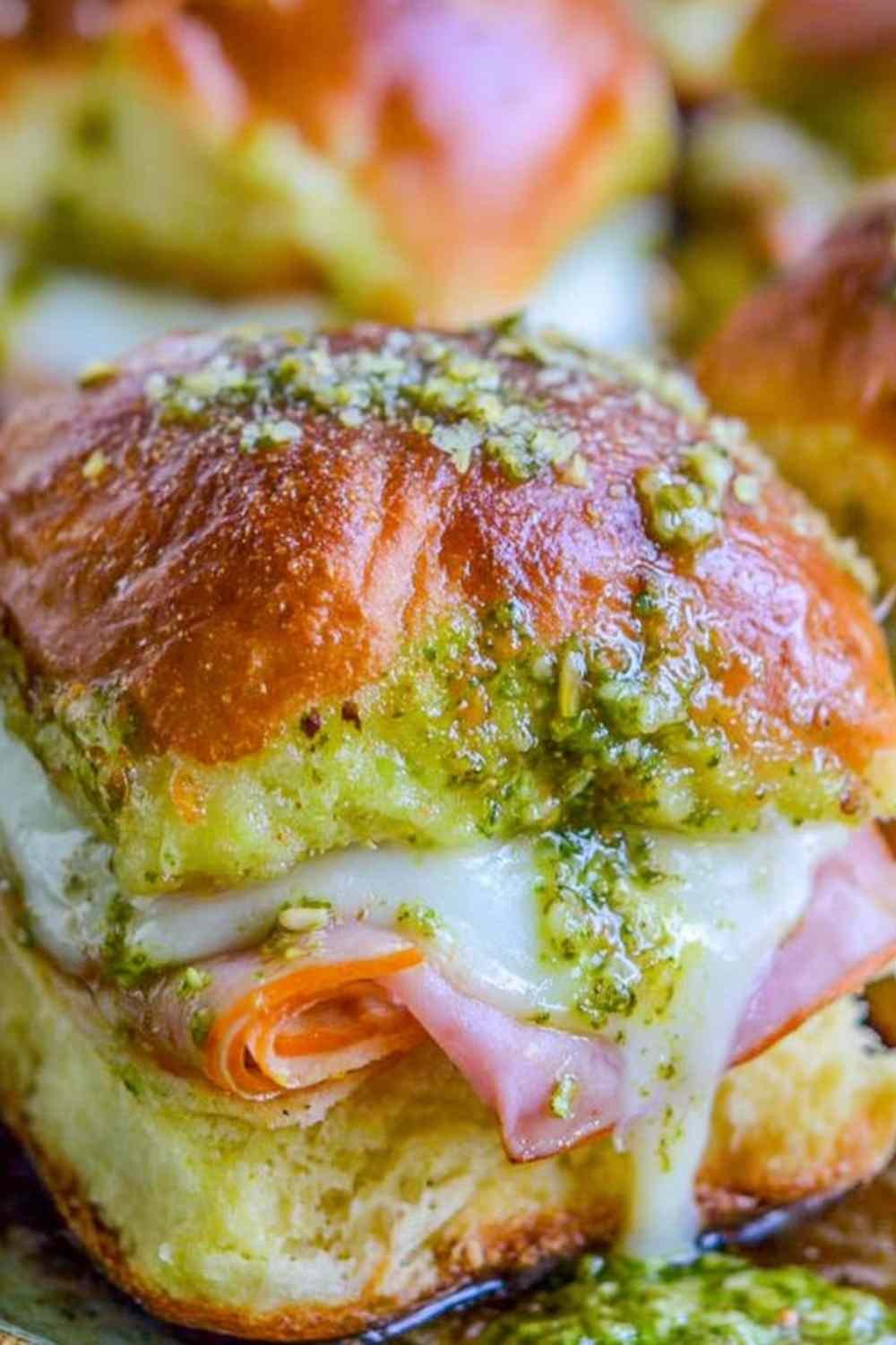 Canadian Bacon and Havarti Cheese Sliders with pesto glaze on a baking sheet, golden and bubbly fresh from the oven