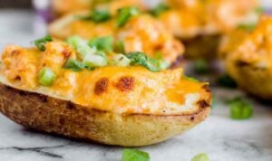 Cheesy buffalo chicken boats on a baking sheet topped with green onions