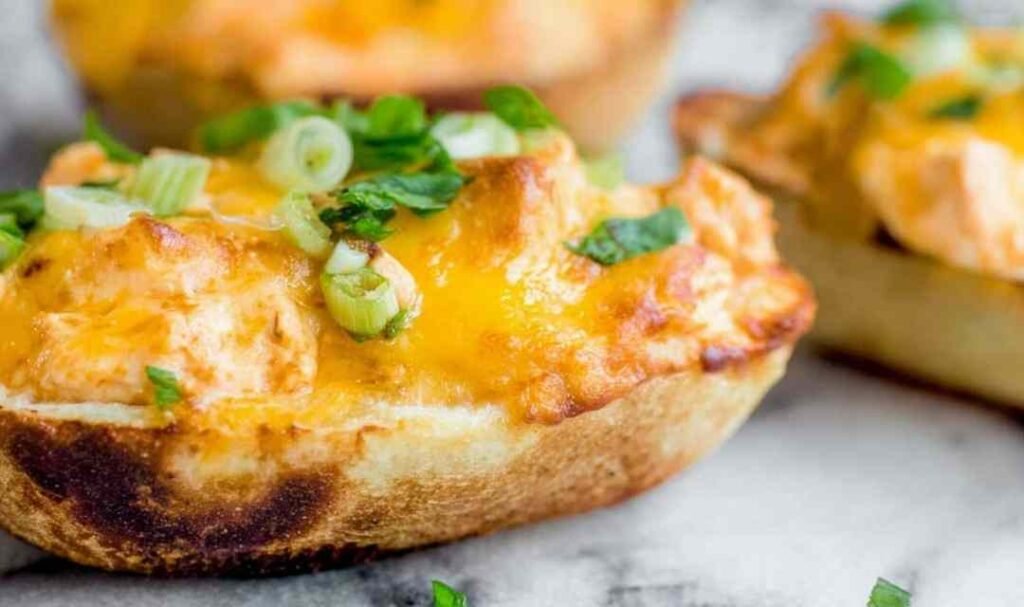 Cheesy buffalo chicken boats on a baking sheet topped with green onions