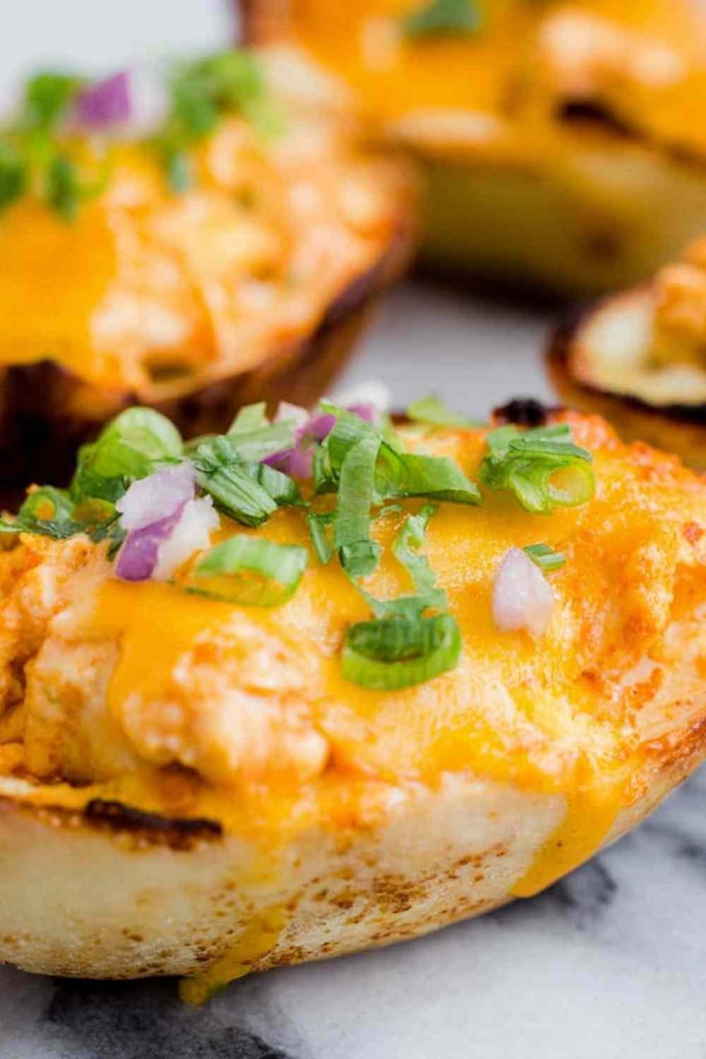 Cheesy buffalo chicken boats on a baking sheet topped with green onions