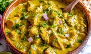 Chicken curry simmering in a skillet with fresh cilantro