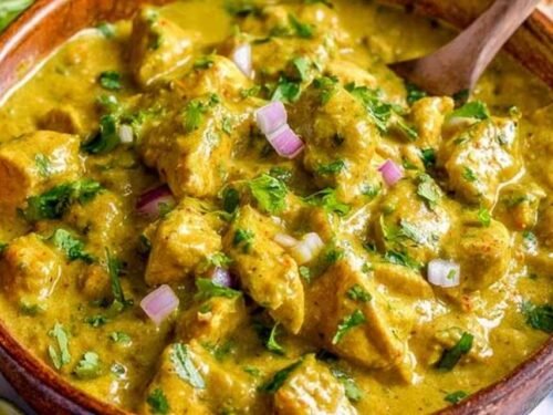 Chicken curry simmering in a skillet with fresh cilantro
