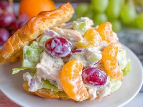 Chicken salad with mandarin oranges and grapes served on a croissant sandwich on a white plate