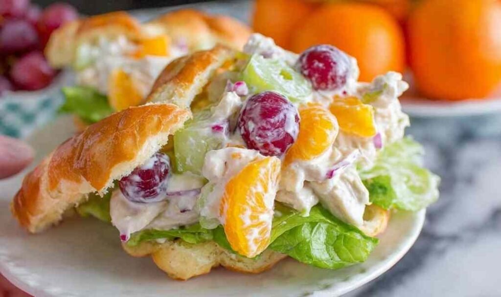 Chicken salad with mandarin oranges and grapes served on a croissant sandwich on a white plate