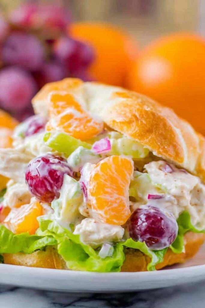 Chicken salad with mandarin oranges and grapes served on a croissant sandwich on a white plate