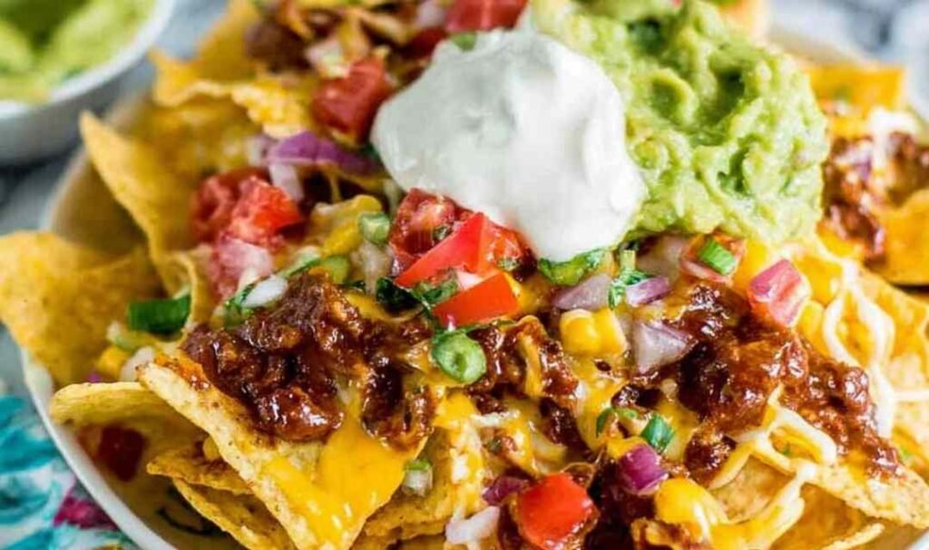 Easy rotisserie chicken nachos loaded with melted cheese and black beans fresh from the oven on a sheet pan