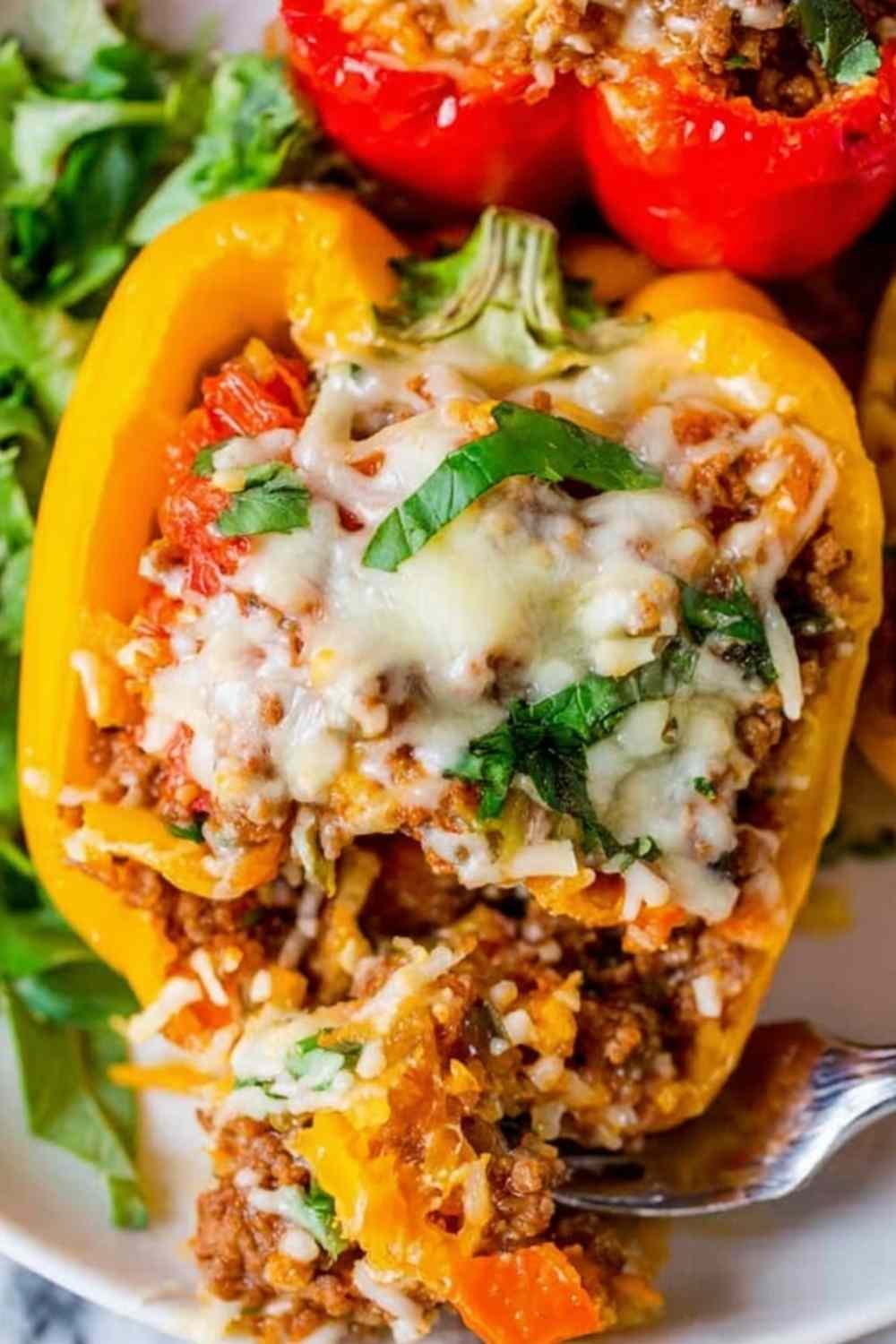 Classic stuffed bell peppers topped with golden melted mozzarella cheese in a white baking dish fresh from the oven