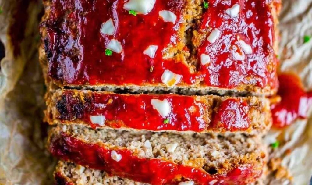 Sliced cream cheese stuffed meatloaf showing a creamy filling on a white serving plate