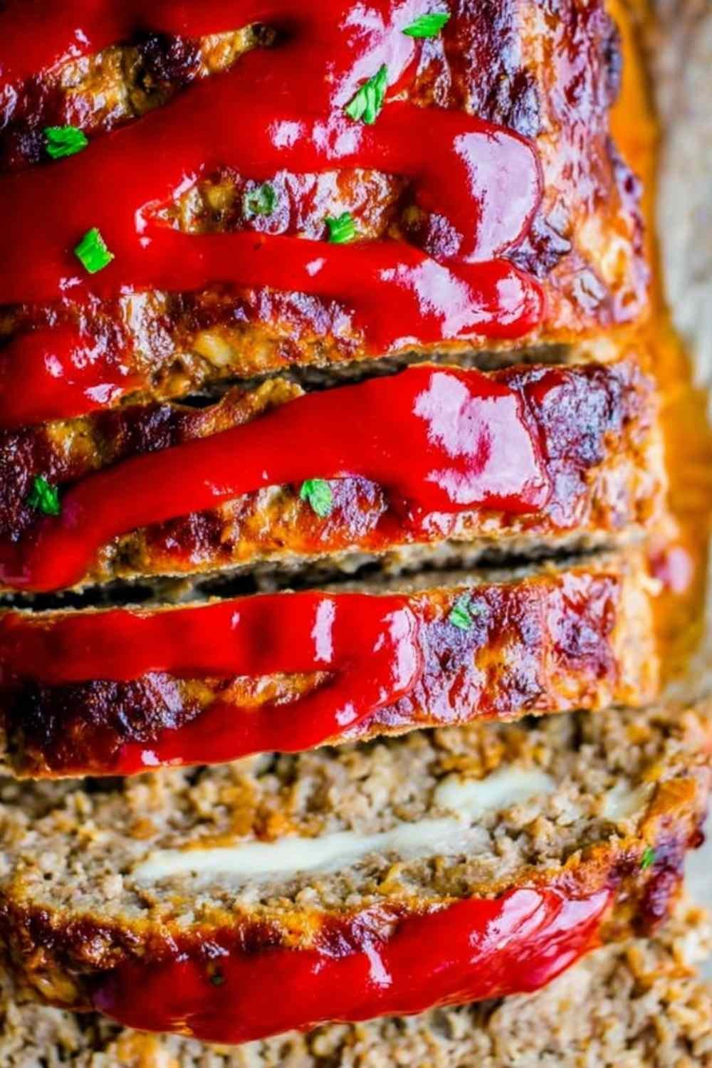 Sliced cream cheese stuffed meatloaf showing a creamy filling on a white serving plate