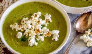 Bowl of creamy zucchini soup topped with popcorn
