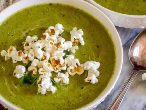 Bowl of creamy zucchini soup topped with popcorn