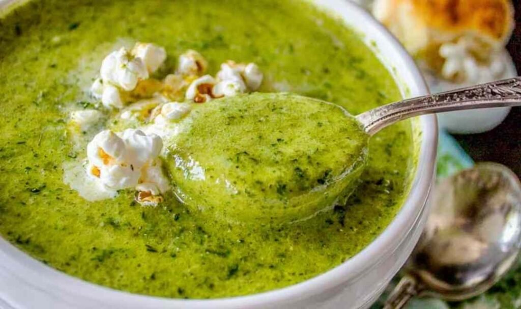 Bowl of creamy zucchini soup topped with popcorn